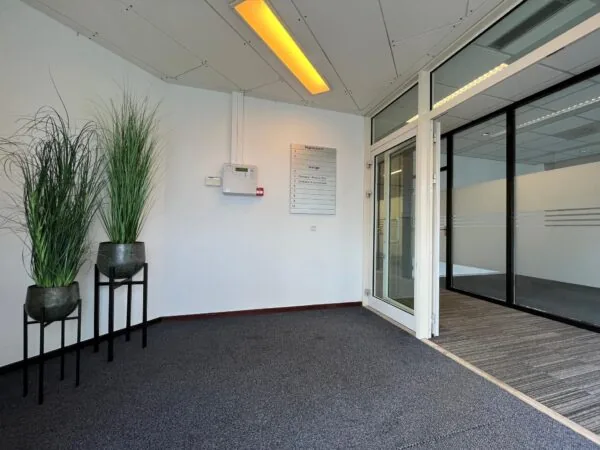 Inkomhal van een kantoor aan de Utrechtseweg met planten, een naambord en glazen kantoordeuren.