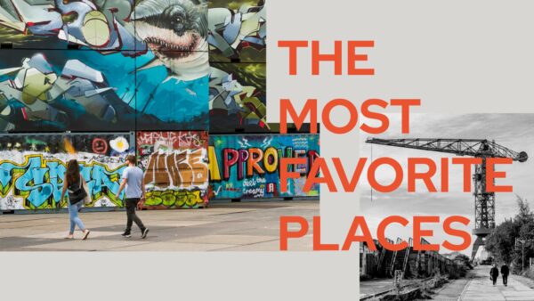 Twee mensen lopen langs kleurrijke graffiti en muurschilderingen op de NDSM-werf in Amsterdam, met de tekst "The Most Favorite Places" over het beeld.
