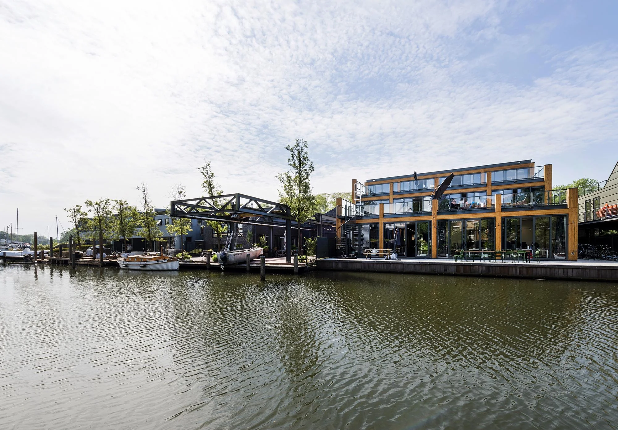 Moderne bebouwing en afgemeerde boten aan het water van de Nieuwendammerkade in Amsterdam.