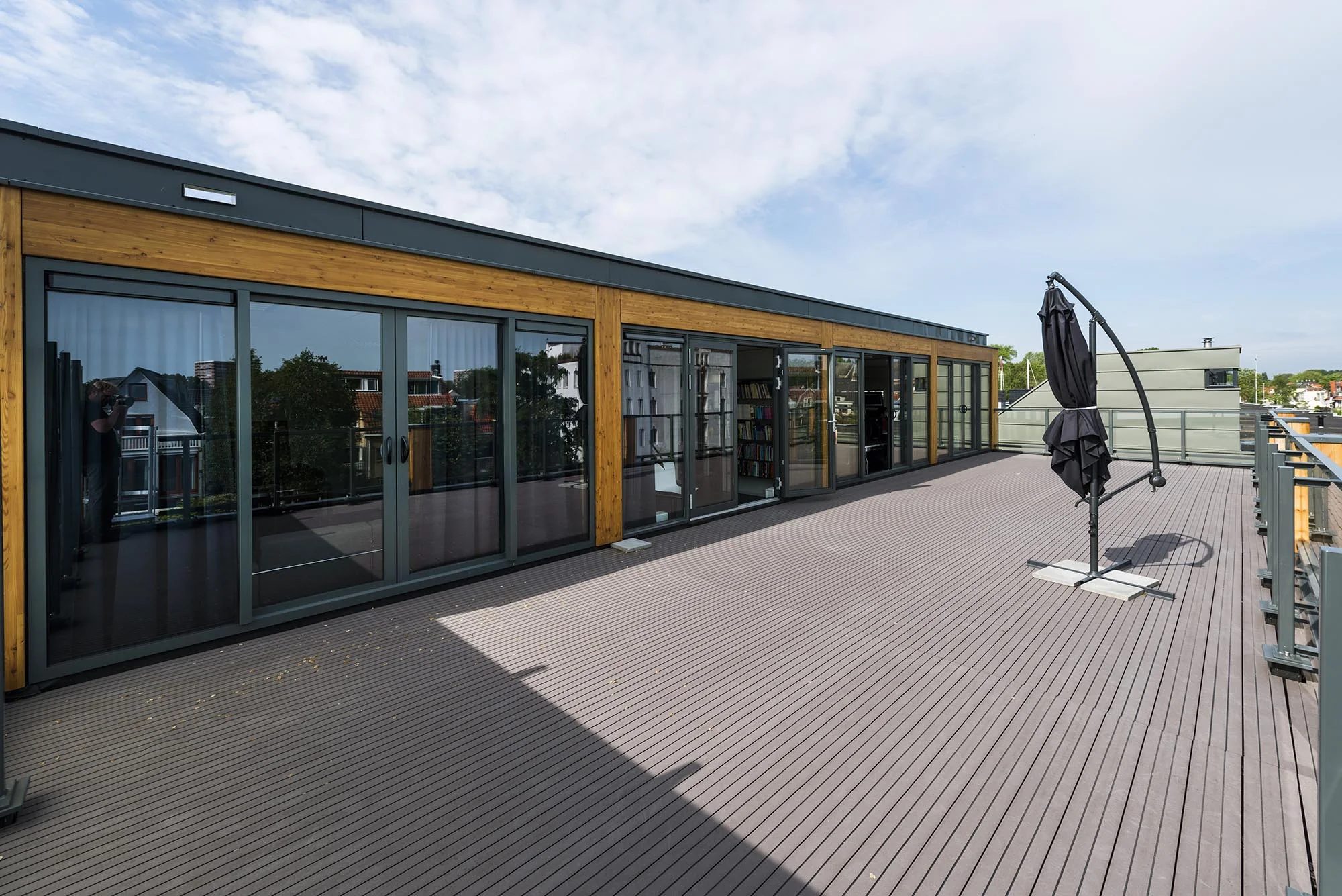 Ruim dakterras aan de Nieuwendammerkade met houten vlondervloer, glazen schuifdeuren en een inklapbare parasol.
