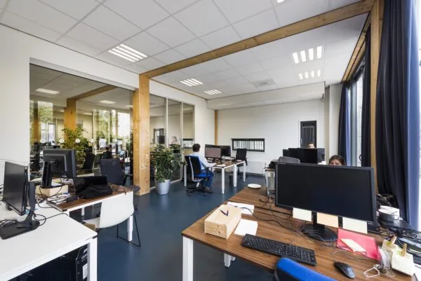 Modern kantoorinterieur aan de Nieuwendammerkade met werkplekken, computers en medewerkers in een open ruimte met veel daglicht.