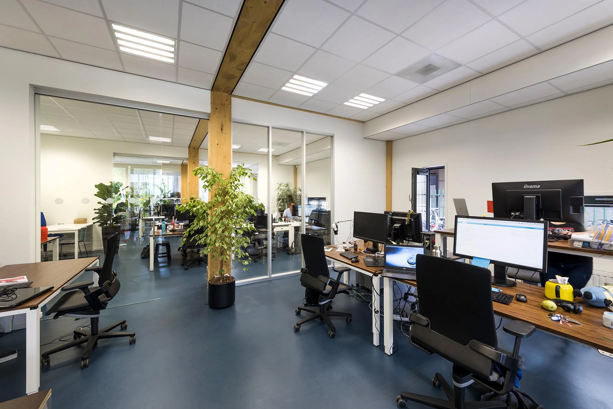 Moderne kantoorruimte aan de Nieuwendammerkade met meerdere bureaus, computers en glazen scheidingswanden.