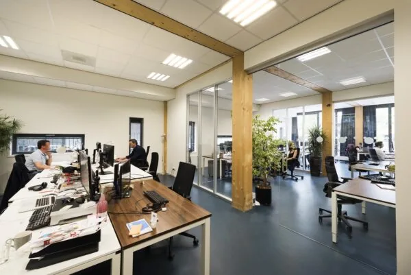 Moderne kantoorruimte aan de Nieuwendammerkade met houten elementen, glazen scheidingswanden en werkende mensen aan bureaus.