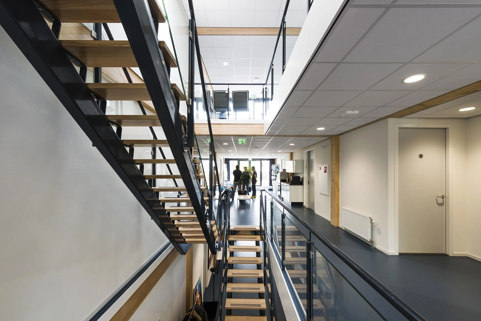 Moderne kantoorruimte aan de Nieuwendammerkade met een open trap, glazen balustrades en zicht op de centrale hal.