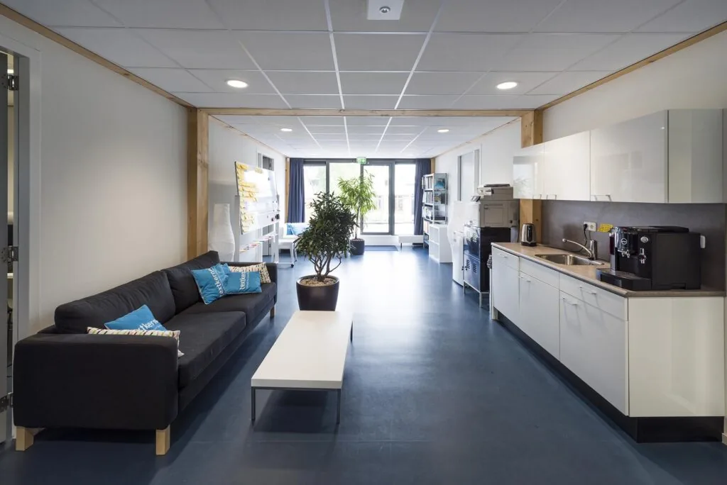 Moderne gemeenschappelijke ruimte aan de Nieuwendammerkade met zithoek, kitchenette en kantoorvoorzieningen.
