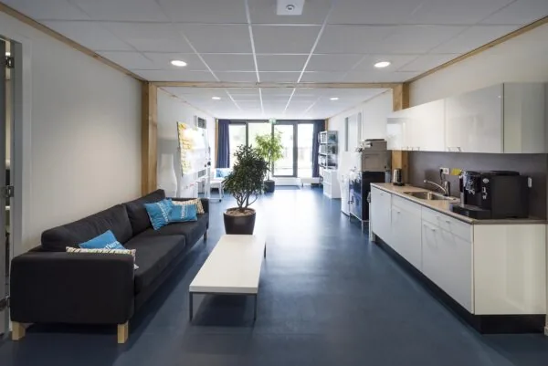 Moderne gemeenschappelijke ruimte aan de Nieuwendammerkade met zithoek, kitchenette en kantoorvoorzieningen.