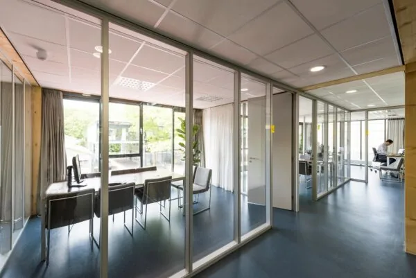 Moderne vergaderruimte en kantoor aan de Nieuwendammerkade met glazen wanden en uitzicht op een groene buitenomgeving.