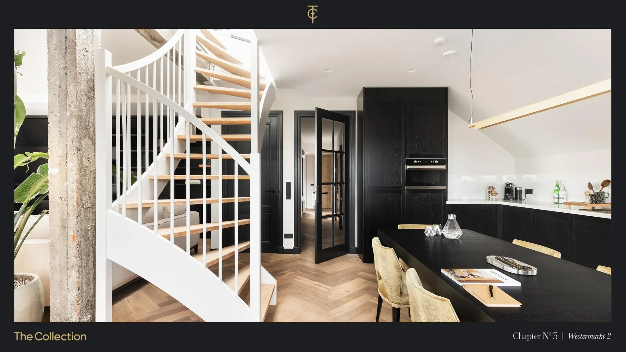 Moderne open keuken en eetruimte met zwarte kasten, houten visgraatvloer en een witte wenteltrap, gelegen aan de Westermarkt.