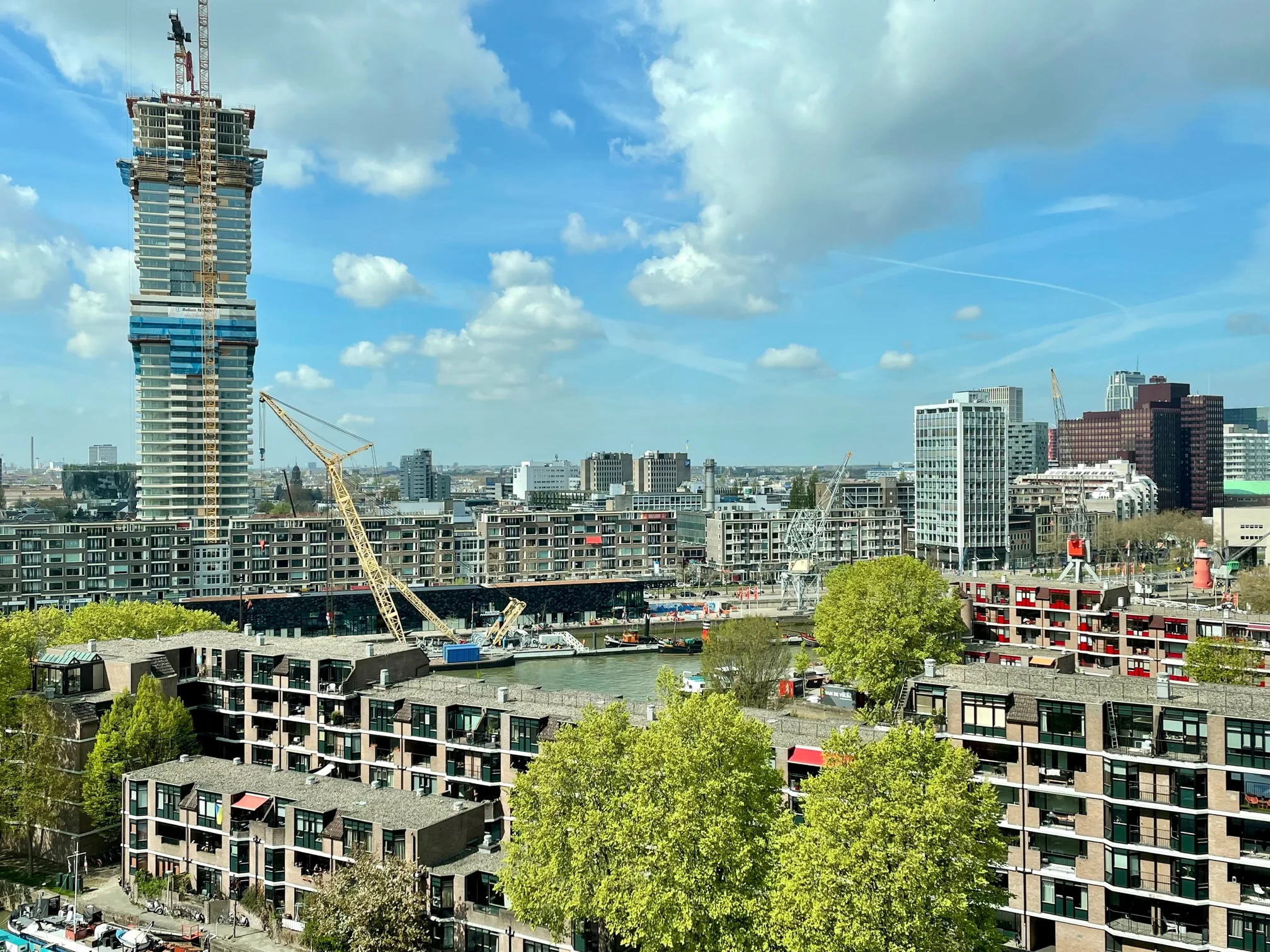 Luchtfoto van het Boompjesgebied in Rotterdam met hoogbouw, hijskranen en de rivier de Maas.