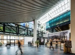 Moderne en lichte binnenruimte aan de Oostenburgermiddenstraat met een eetgelegenheid, glazen daken en wandelende mensen.