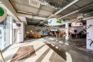 Moderne, industrieel ingerichte ontmoetingsruimte aan de Oostenburgermiddenstraat met zitgedeeltes, kunstwerken en aanwezige mensen.