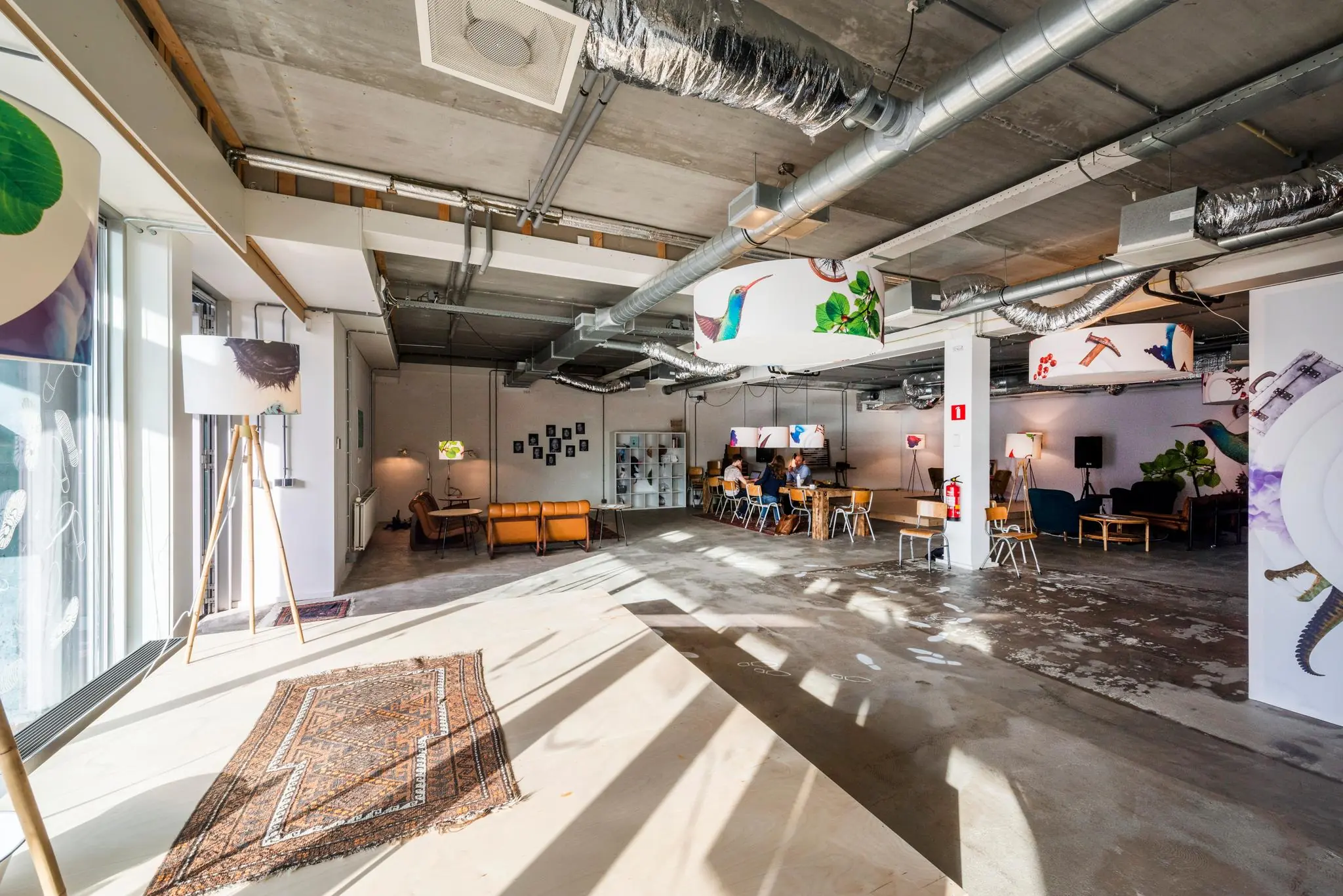 Moderne, industrieel ingerichte ontmoetingsruimte aan de Oostenburgermiddenstraat met zitgedeeltes, kunstwerken en aanwezige mensen.