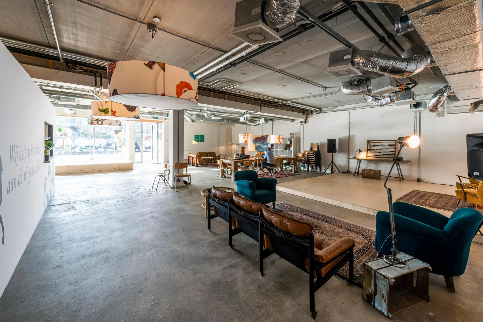 Open en modern ingericht multifunctioneel interieur aan de Oostenburgermiddenstraat met zitgelegenheid, werkplekken en een podium.