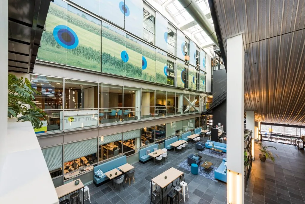 Moderne, open kantoorruimte aan de Oostenburgermiddenstraat met meerdere verdiepingen, glazen wanden en zitgedeeltes.