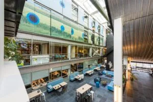 Moderne, open kantoorruimte aan de Oostenburgermiddenstraat met meerdere verdiepingen, glazen wanden en zitgedeeltes.