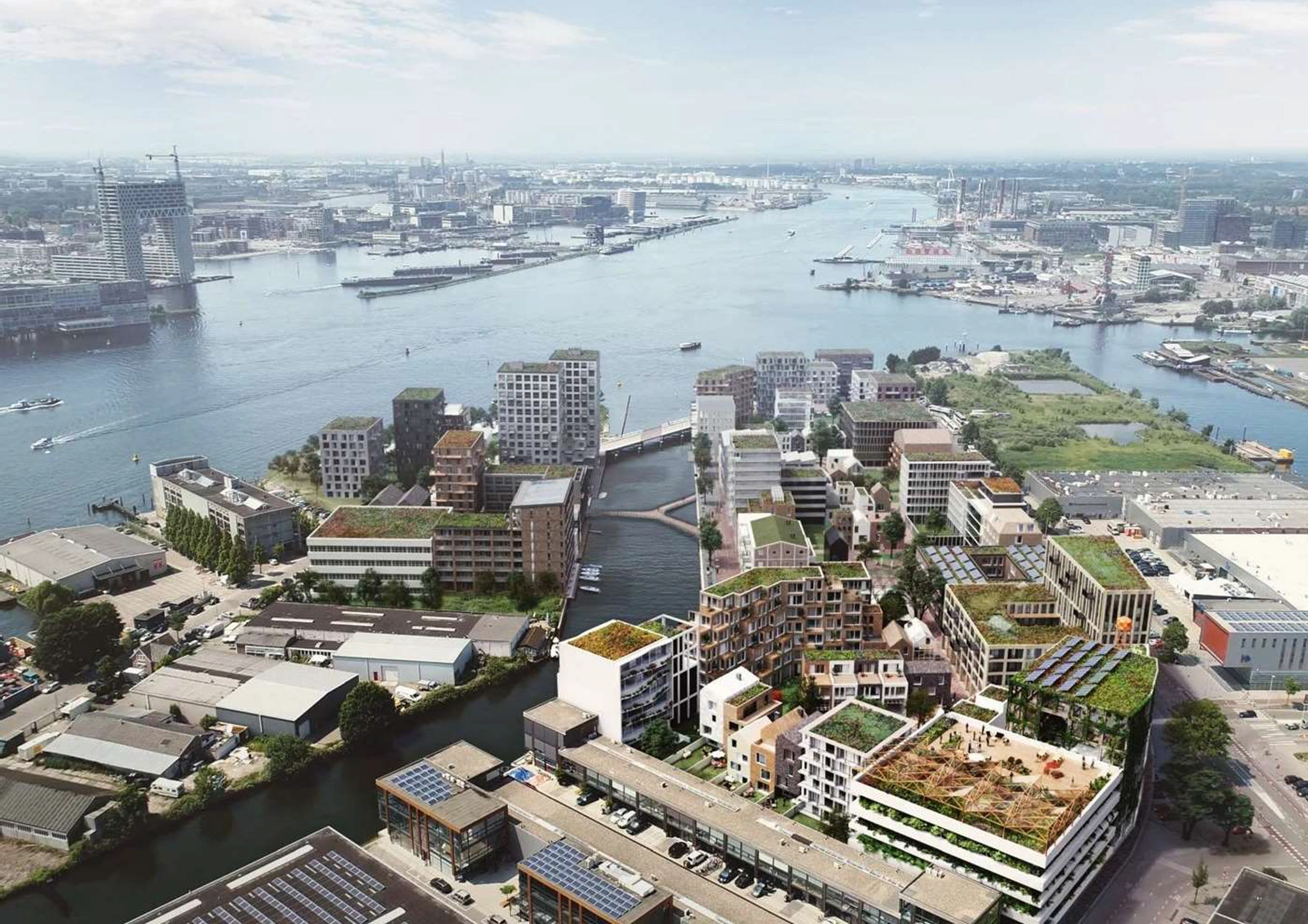 Luchtfoto van de Grasweg in Amsterdam met moderne woningbouwprojecten langs het water en groene daken.