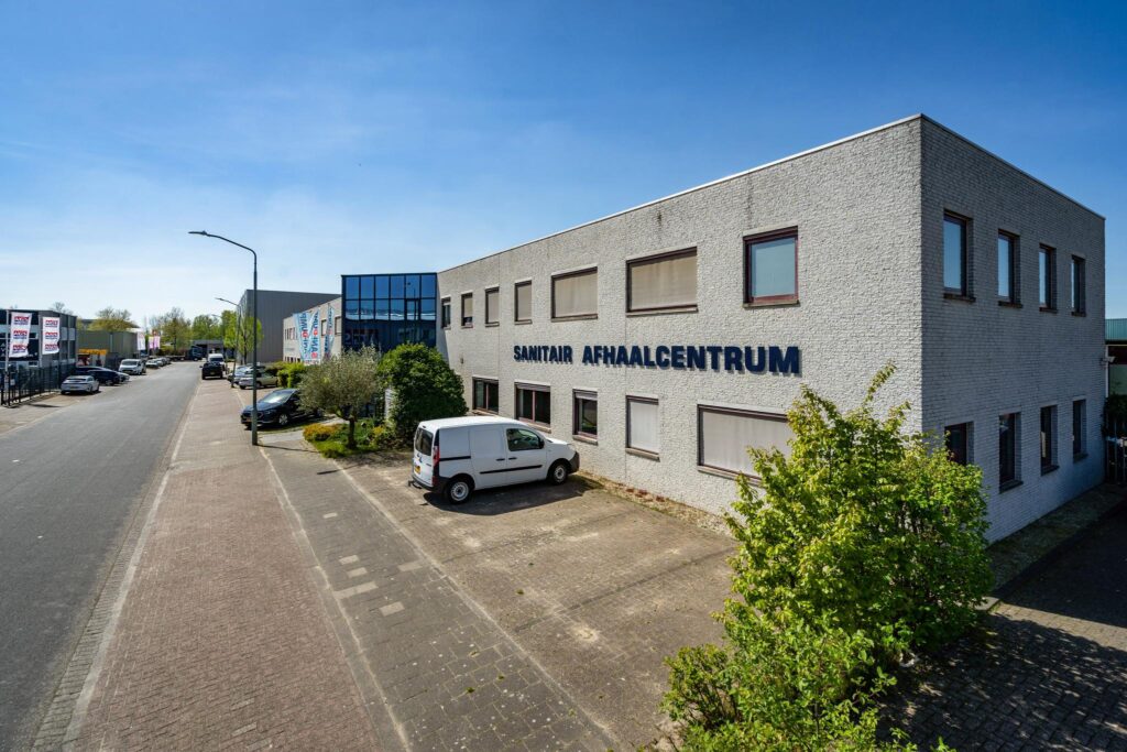 Voorgevel van het bedrijfspand "Sanitair Afhaalcentrum" aan de Daltonstraat met een geparkeerde witte bestelwagen.