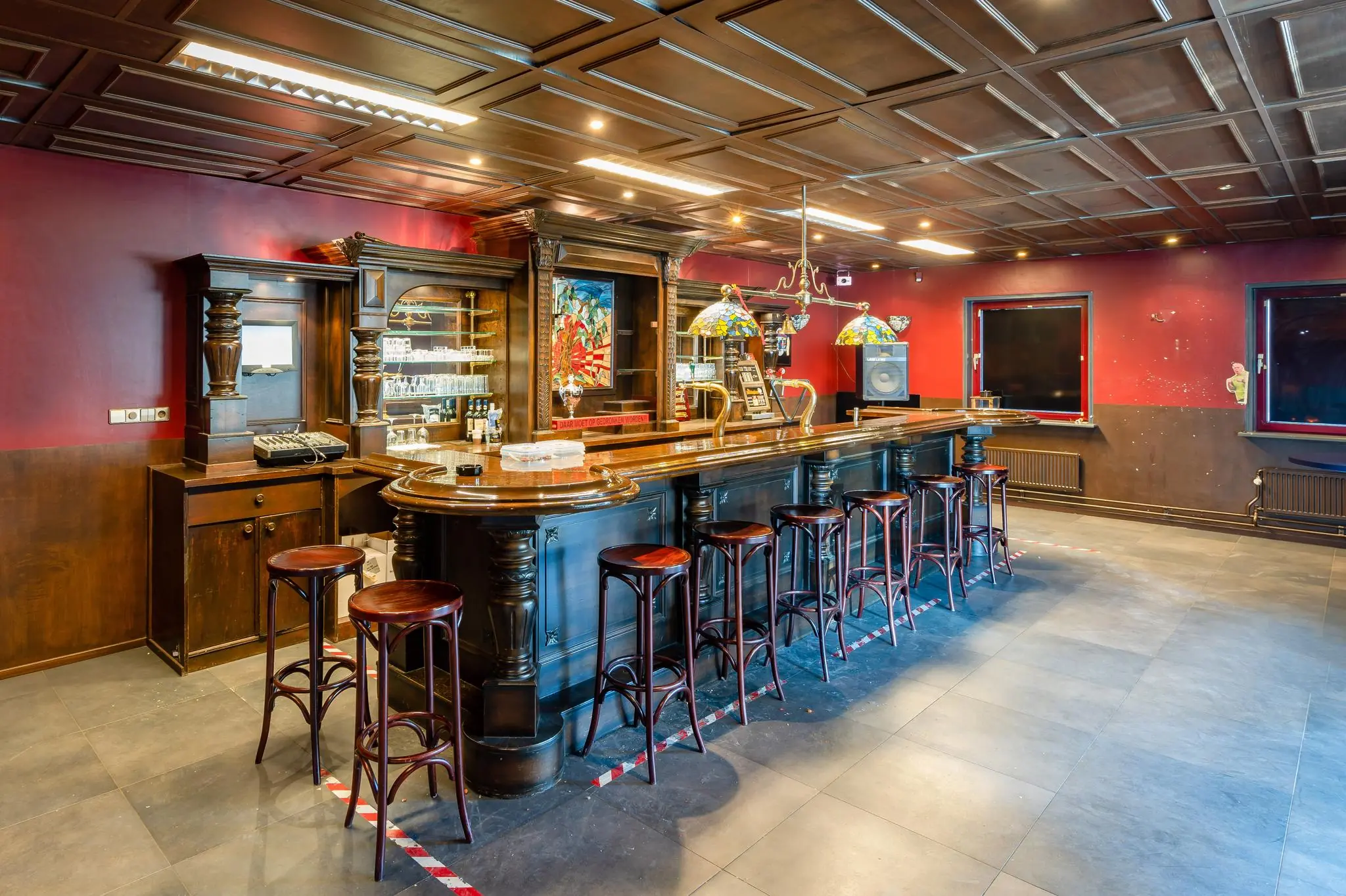 Sfeervolle houten bar met barkrukken en glas-in-loodlampen in een ruimte aan de Daltonstraat.