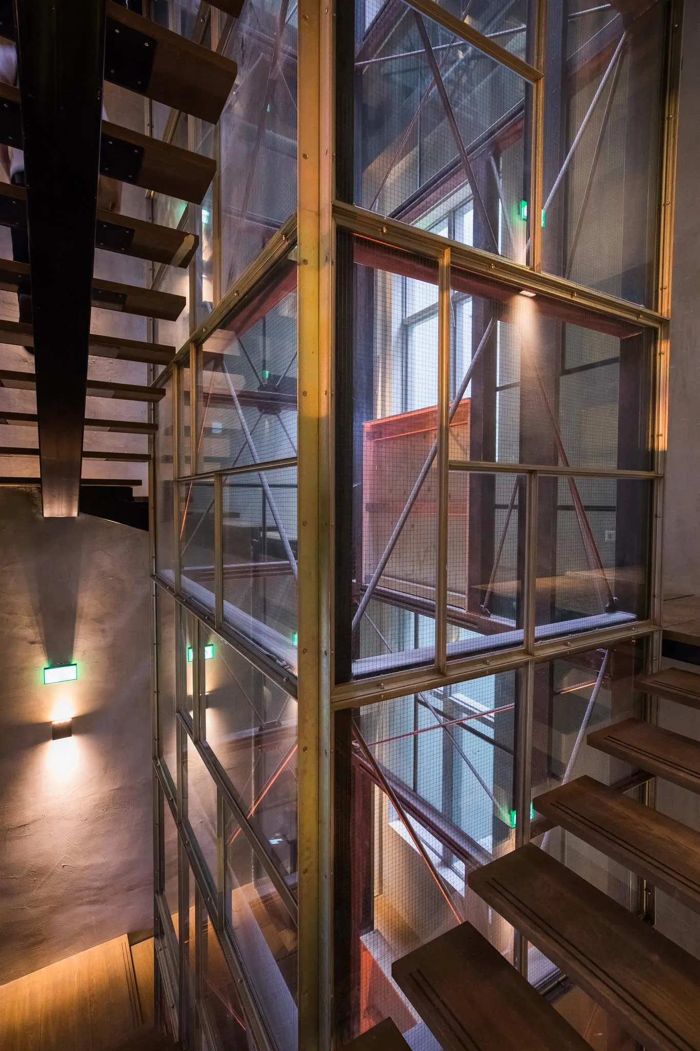Trapopgang met industriële afwerking en glazen liftkoker in een modern gebouw aan de Prins Hendrikkade.