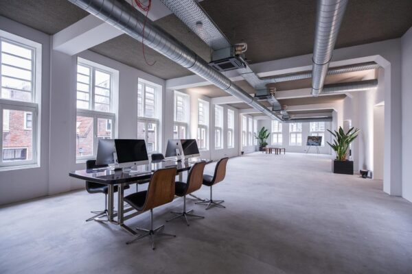 Modern en licht kantoorinterieur aan de Prins Hendrikkade met werkplekken, grote ramen en industriële details.