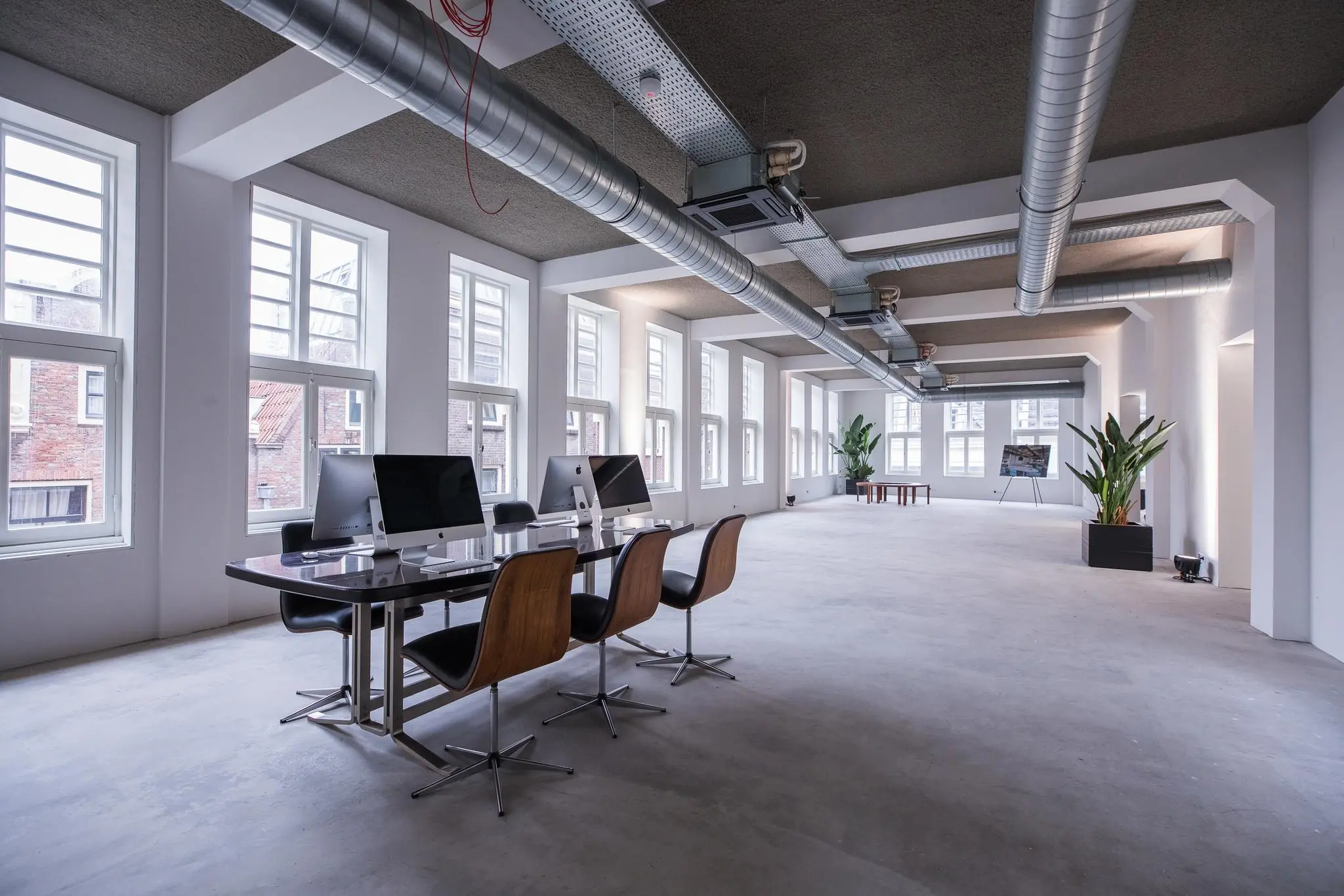 Modern en licht kantoorinterieur aan de Prins Hendrikkade met werkplekken, grote ramen en industriële details.
