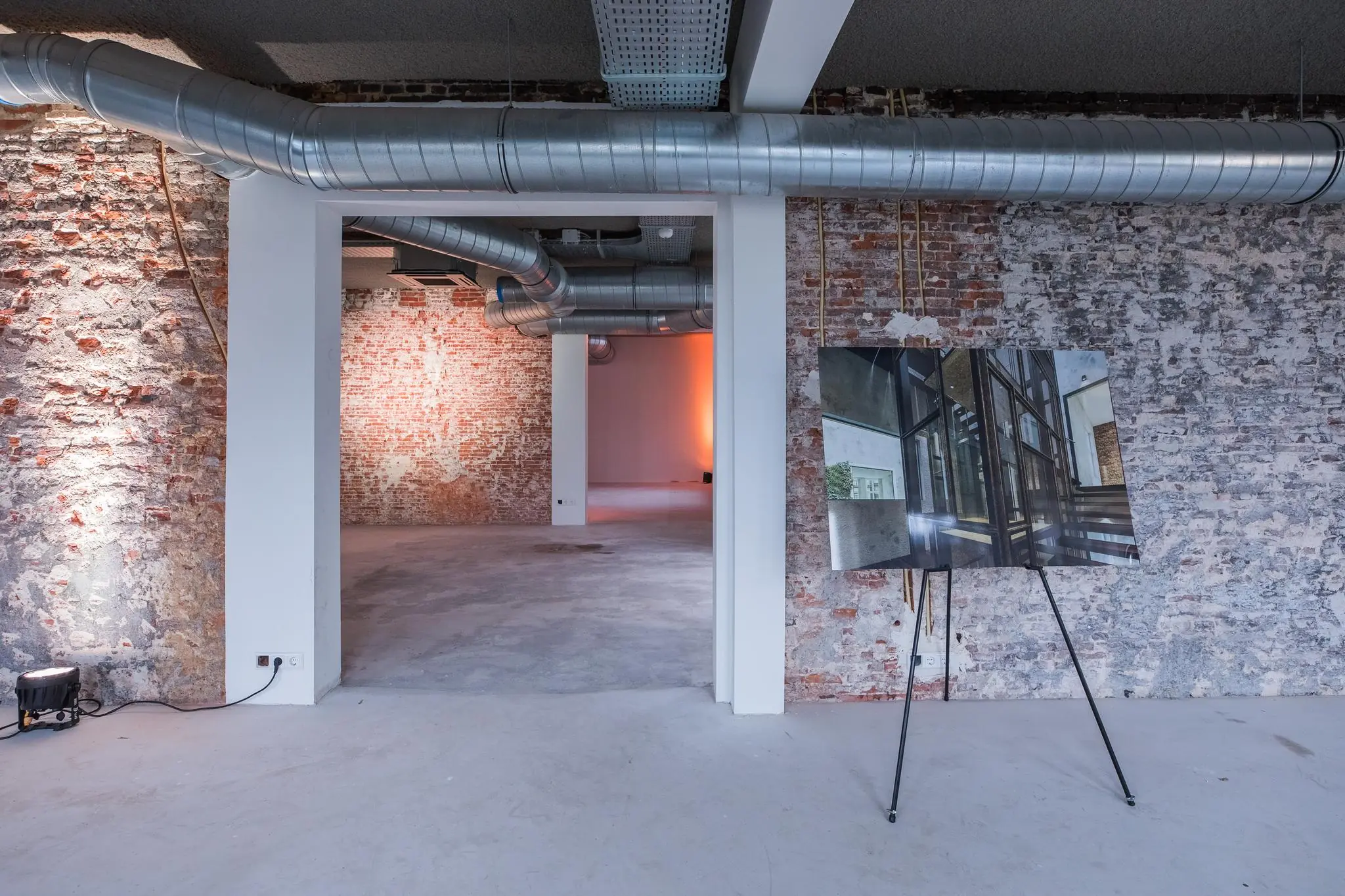 Industriële binnenruimte aan de Prins Hendrikkade met zicht op ruwe bakstenen muren, zichtbare ventilatiebuizen en een architectonisch ontwerp op een schildersezel.