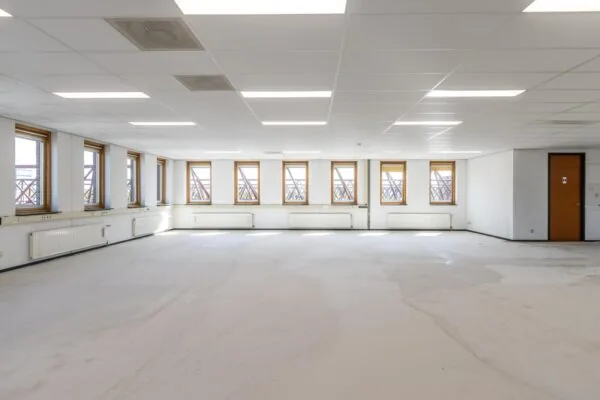 Leeg kantoorpand met systeemplafond, meerdere ramen en een gesloten deur, gelegen aan de Veldzigt.