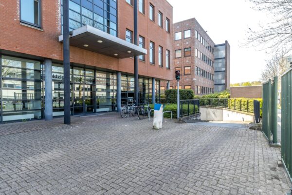 Ingang van het Veldzigt-kantoorgebouw met fietsenstalling en oprit naar de parkeergarage.