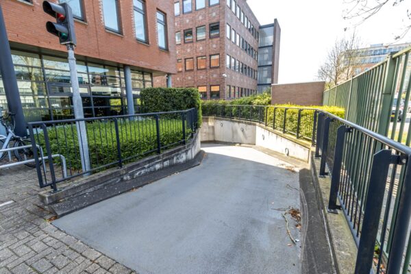 Ingang van een parkeergarage bij het kantoorgebouw Veldzigt, omgeven door een rood bakstenen gevel en zwart metalen hekwerk.