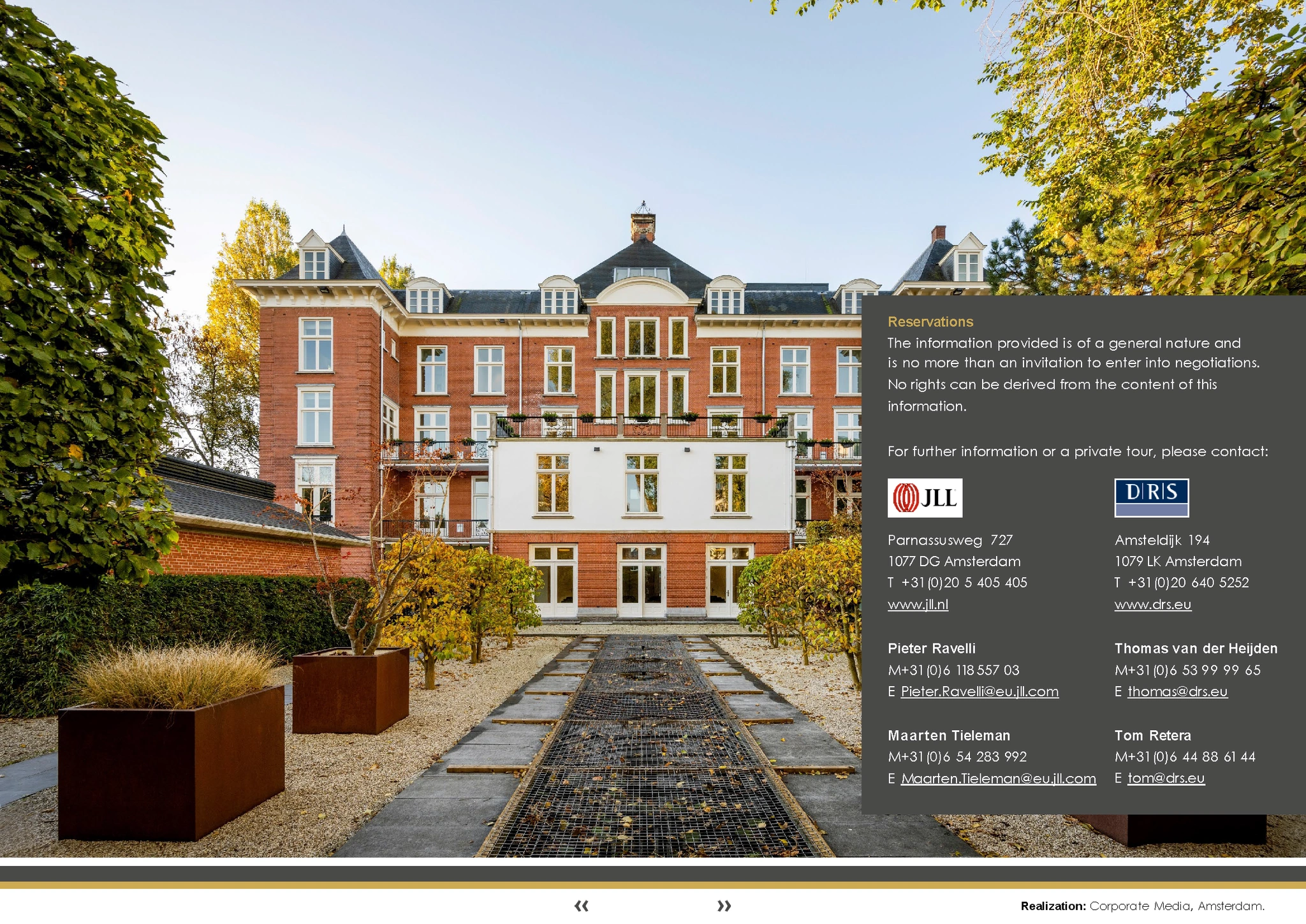 Roodbakstenen kantoorpand aan het Museumplein in Amsterdam, omgeven door een verzorgde tuin met herfstkleurige bomen.