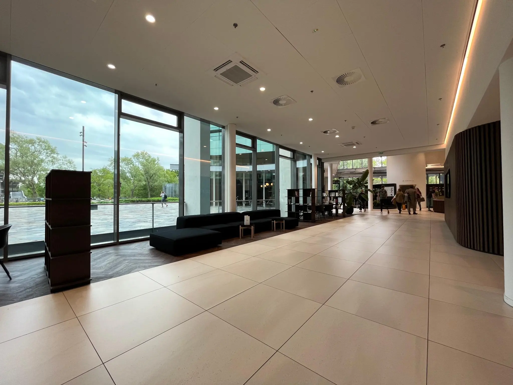 Ruim en modern ingerichte lobby van een gebouw aan het Herculesplein met grote ramen en zitgelegenheid.