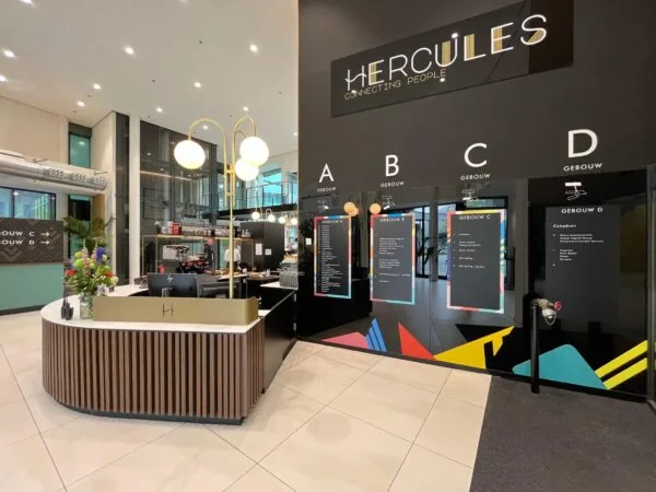 Moderne ontvangstbalie in de entree van het Herculesgebouw met wegwijzers naar gebouwen A t/m D.