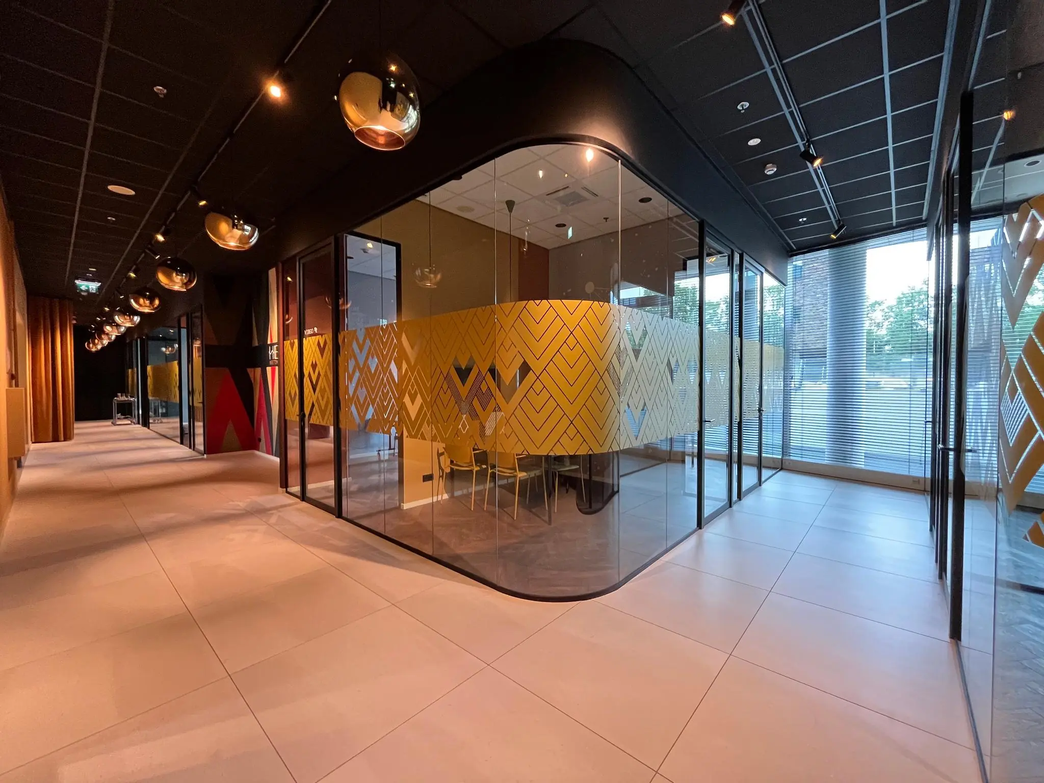 Moderne kantoorruimte aan het Herculesplein met glazen vergaderruimtes en geel patroon op de ramen.