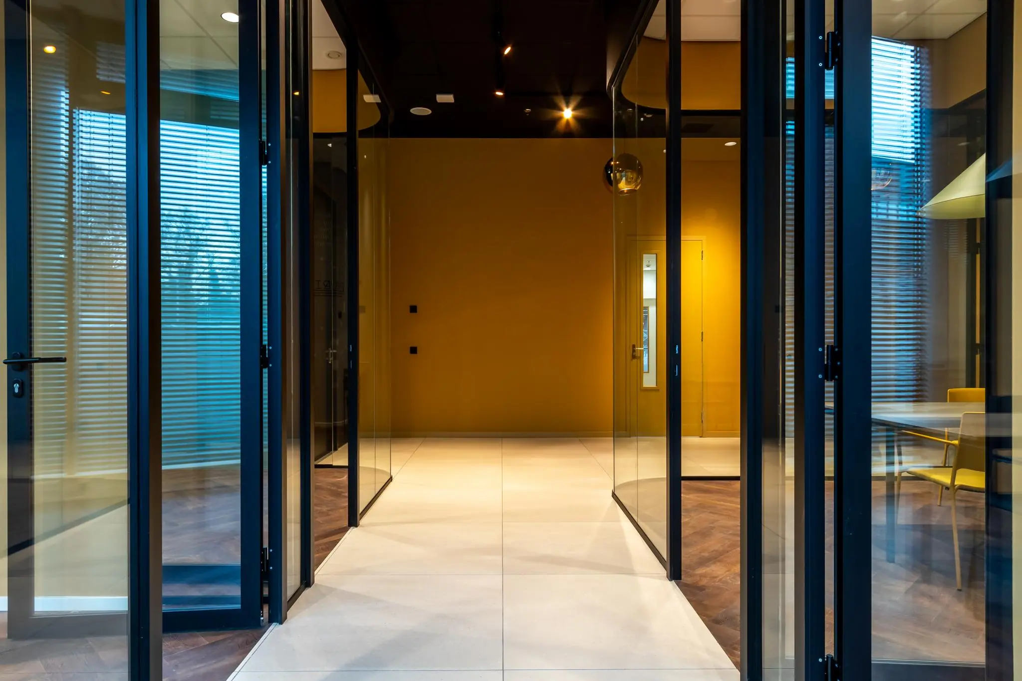 Moderne entree met glazen deuren en gele wanden in een kantoorpand aan het Herculesplein.
