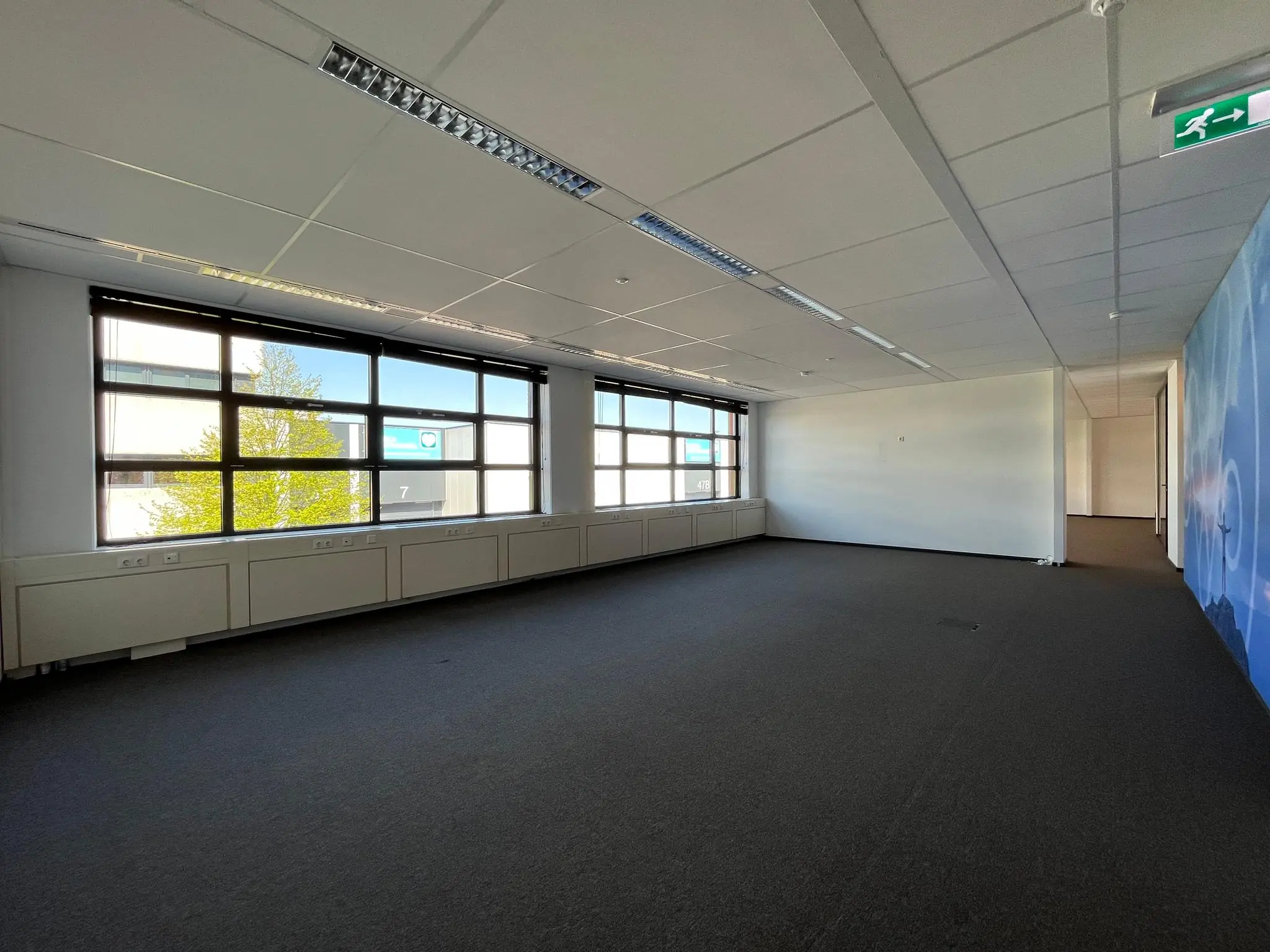 Leeg kantoorpand aan de Zonnebaan met grote ramen en systeemplafond.