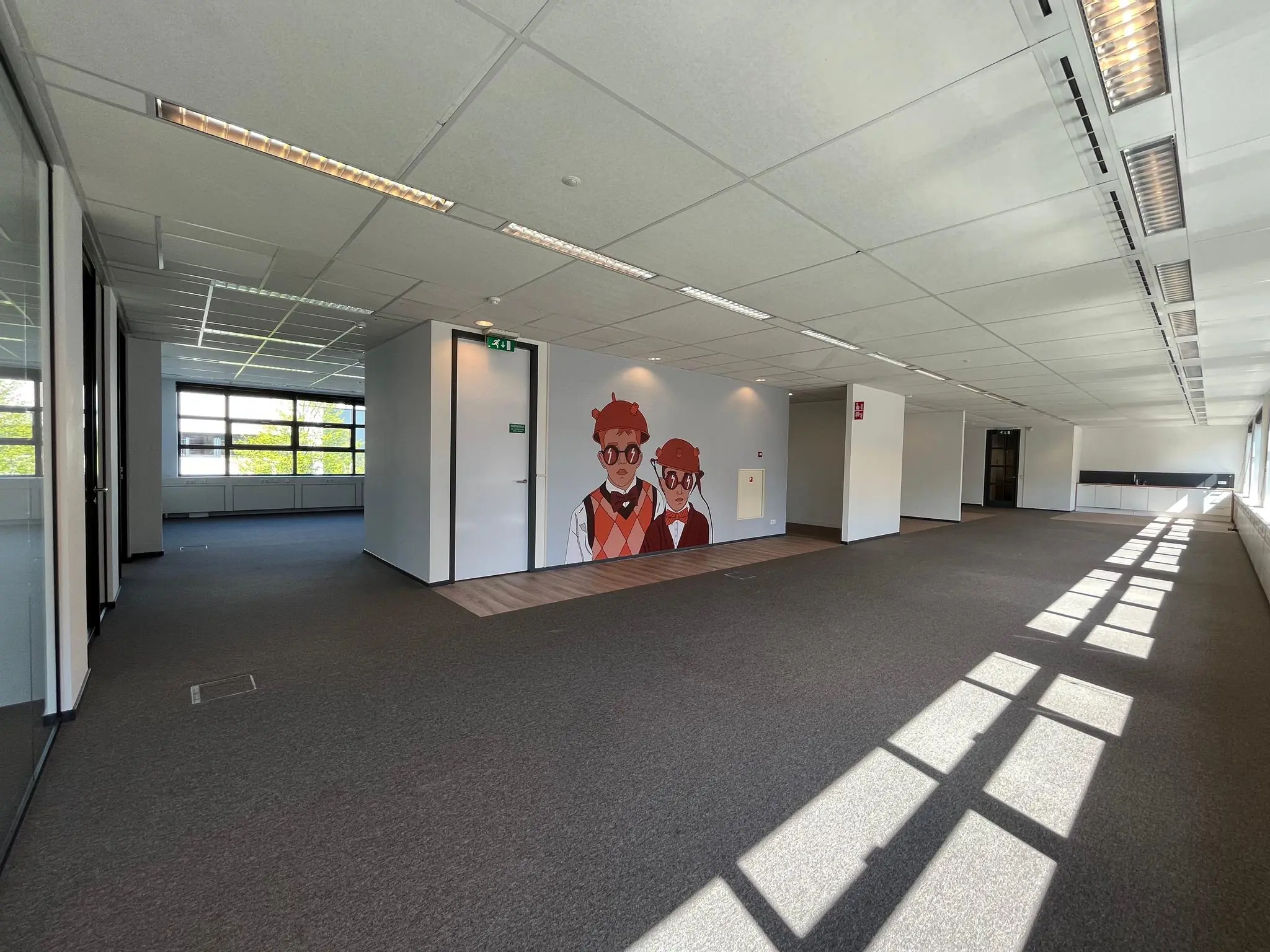 Licht en ruim kantoorpand aan de Zonnebaan met een muurschildering van twee getekende figuren.