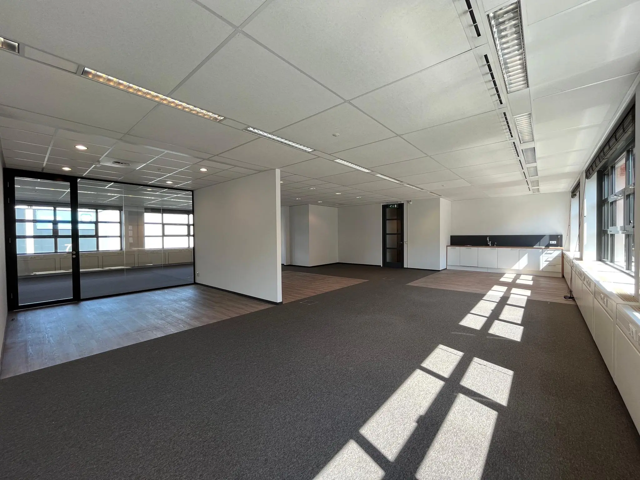 Licht en modern kantoorpand aan de Zonnebaan met grote ramen, open werkruimte en glazen vergaderruimte.