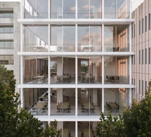 Moderne glazen gevel van een kantoorgebouw aan de Grasweg met zicht op meerdere verdiepingen vol werkplekken.