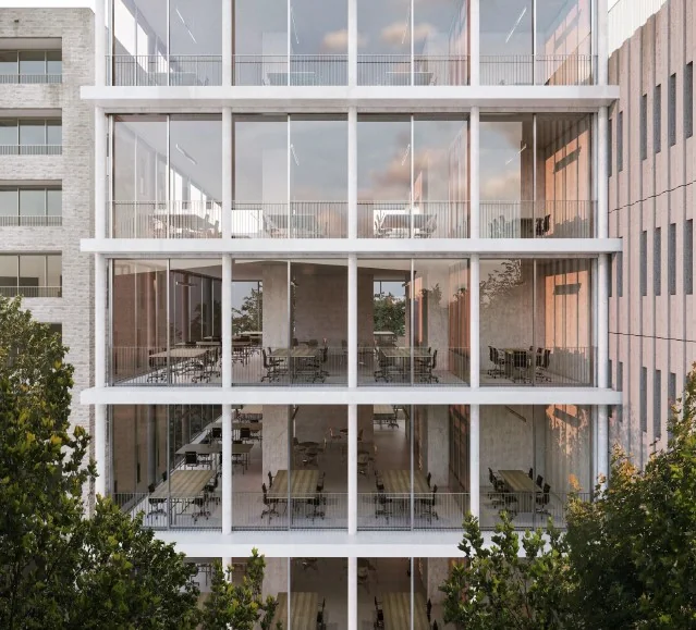 Moderne glazen gevel van een kantoorgebouw aan de Grasweg met zicht op meerdere verdiepingen vol werkplekken.