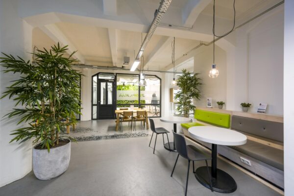 Moderne wachtruimte aan de Van Diemenstraat met groene accenten, zitbanken, tafels en veel planten.