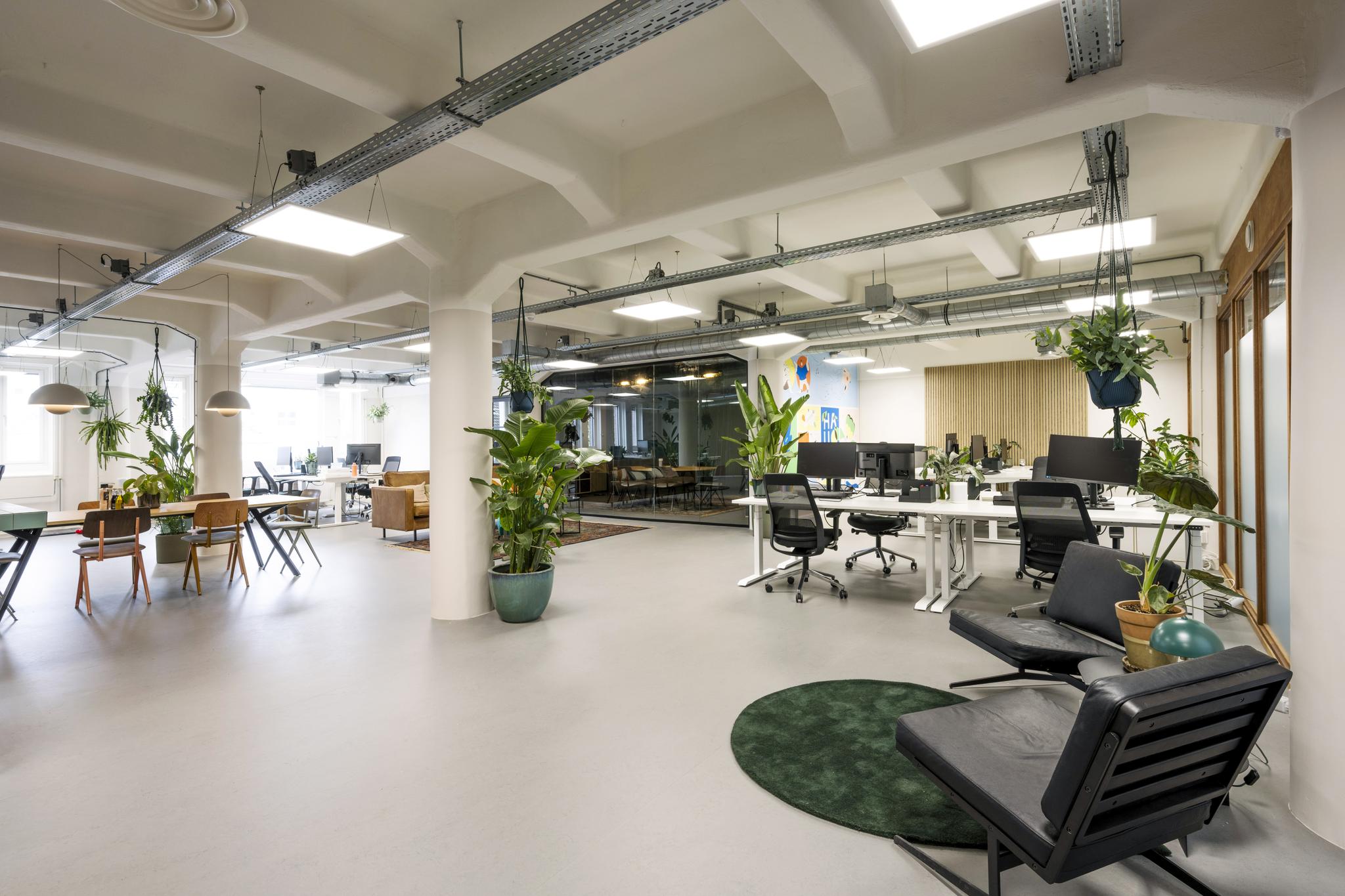 Modern en ruim kantoorinterieur aan de Van Diemenstraat met open werkplekken, groene planten en een glazen vergaderruimte.