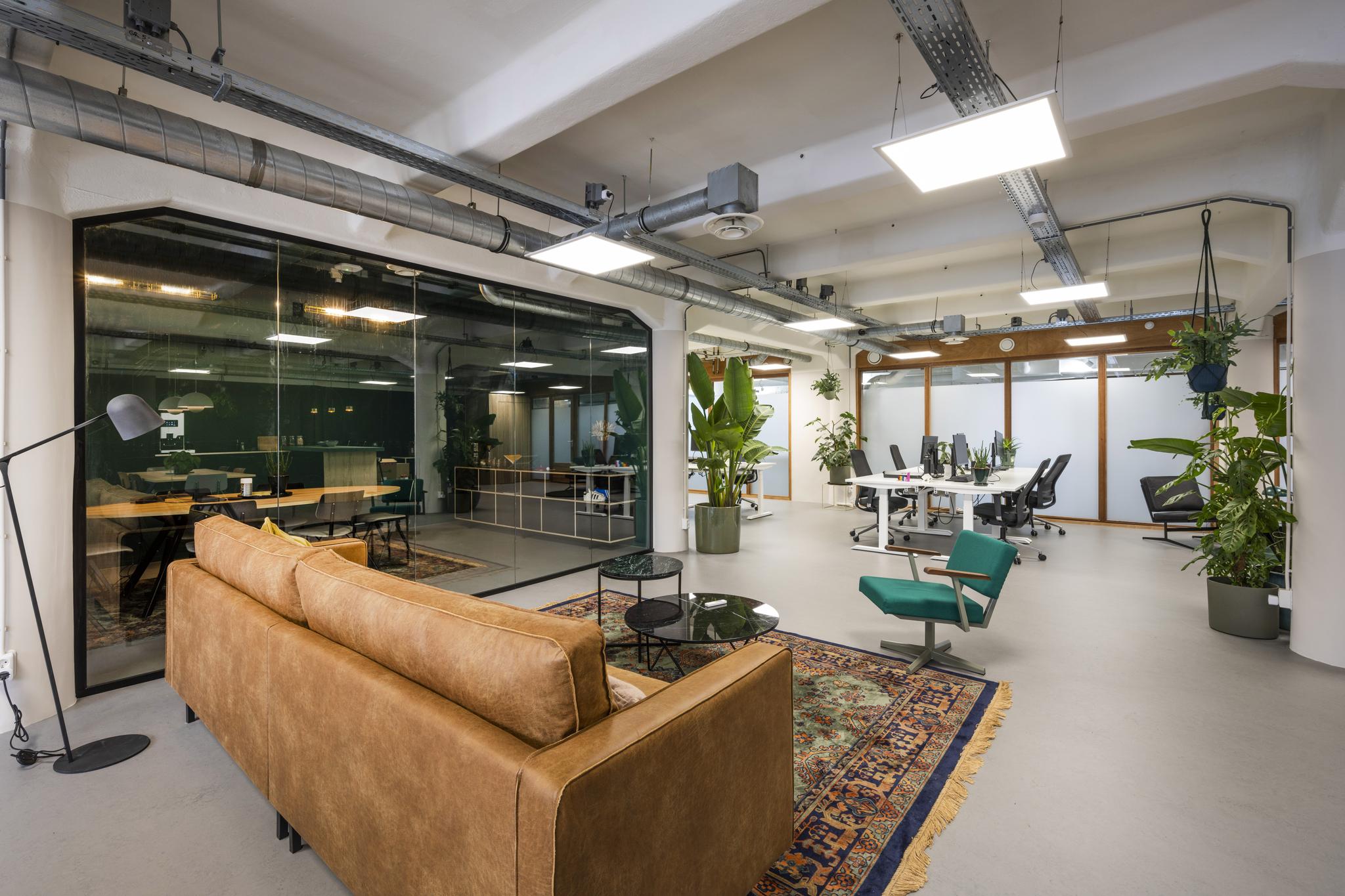 Modern kantoorinterieur aan de Van Diemenstraat met open werkplekken, een zithoek en veel groene planten.
