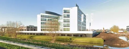 Modern kantoorgebouw aan het Stationspark met omliggend groen en waterpartij.