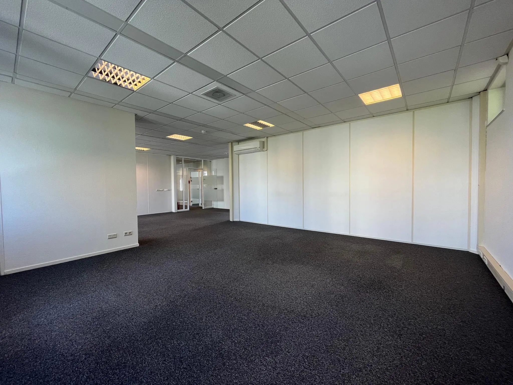 Leeg kantoorruimte met tapijtvloer en systeemplafond aan de Utrechtseweg.