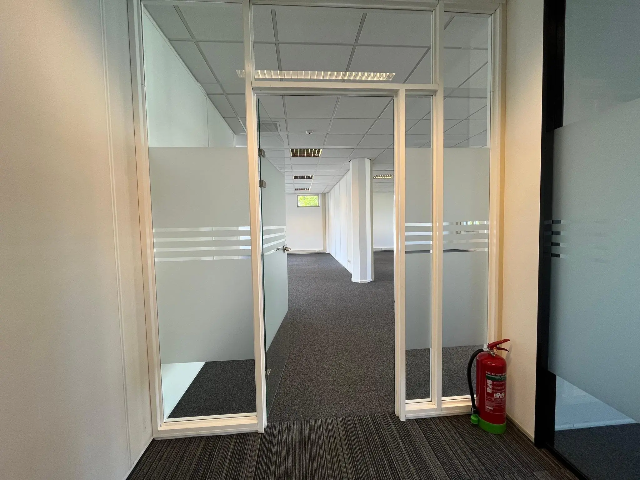Glazen kantoordeur met matte stroken geeft toegang tot een lege kantoorruimte aan de Utrechtseweg, met een brandblusser rechts naast de deur.