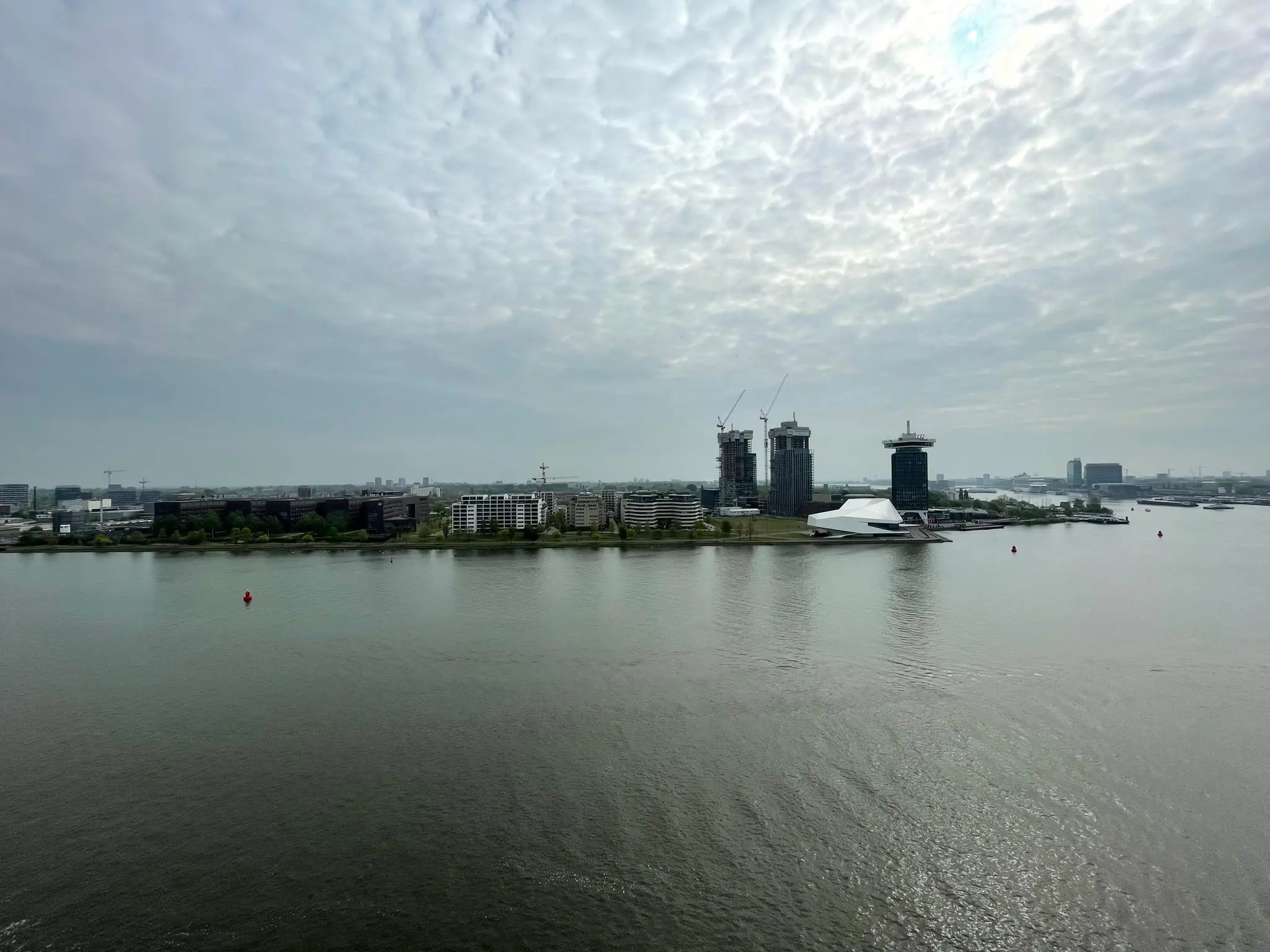 Gezicht op het IJ in Amsterdam met het Eye Filmmuseum, de A'DAM Toren en hoogbouw in aanbouw aan de noordelijke oever.