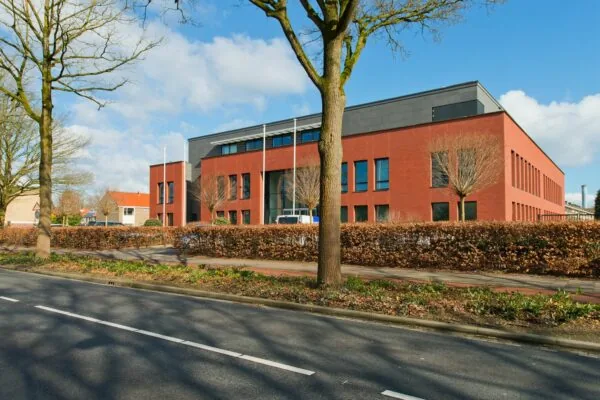 Modern rood bakstenen kantoorgebouw aan de Groene Kanseweg, gefotografeerd vanaf de overzijde van de straat op een zonnige dag.