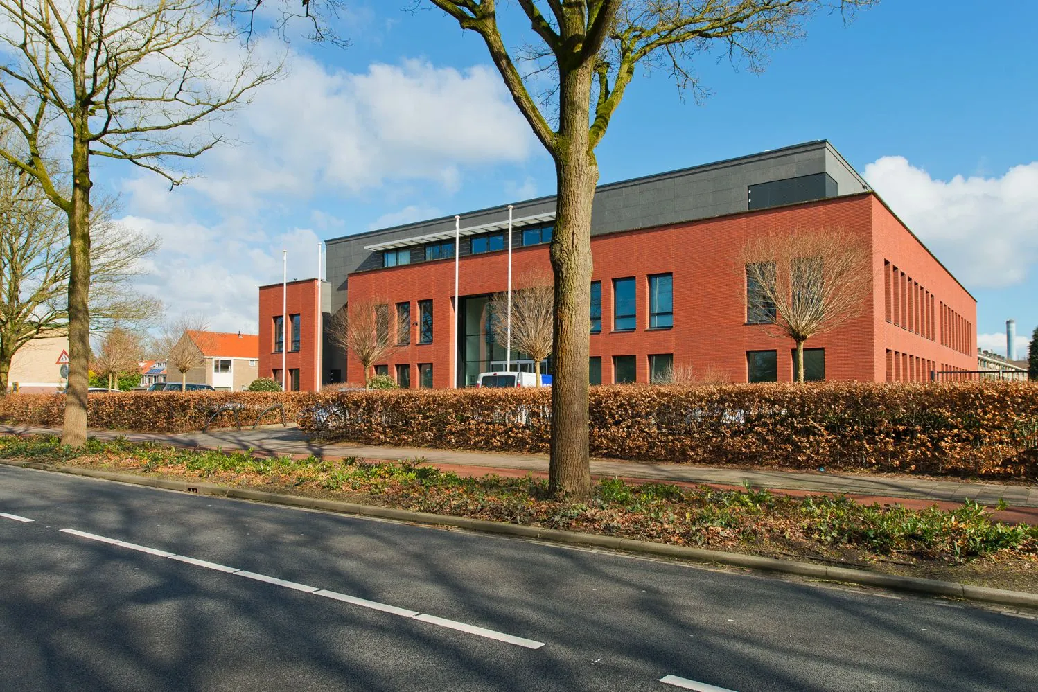 Modern rood bakstenen kantoorgebouw aan de Groene Kanseweg, gefotografeerd vanaf de overzijde van de straat op een zonnige dag.