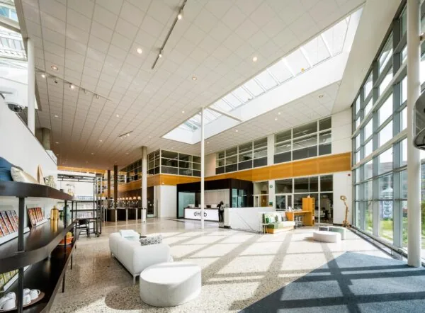 Moderne, lichte en ruime ontvangsthal van een kantoorpand aan de Capellalaan met zithoeken en receptiebalie.