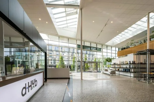 Moderne, lichtovergoten entreehal van een kantoor aan de Capellalaan met ontvangstbalie en open zithoek.